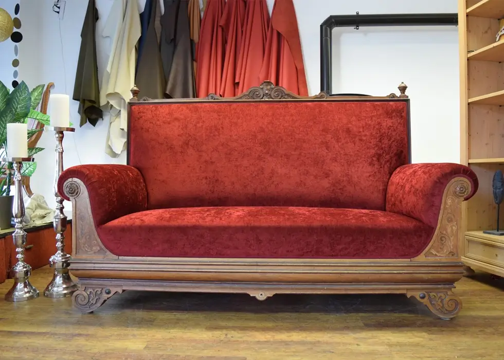 Ein antikes Sofa mit rotem Samtbezug wurde renoviert.