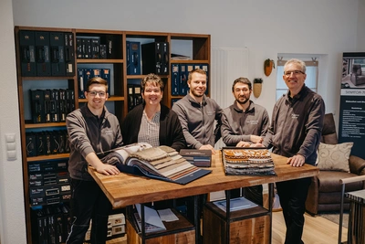 Das gesamte Polsterei Kramer Team steht im Ausstellungsraum zusammen.
